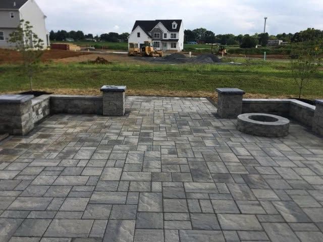 Paver patio with stone pillars and a built-in fire pit